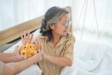 Asian senior woman raised her hand to refuse bread from caregiver