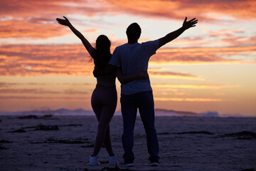 Sunset sky, freedom and couple on beach with silhouette, romance and travel holiday together for...