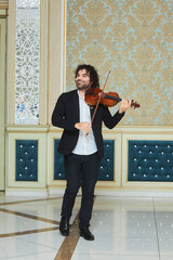 Musician violinist with a violin in his hands standing on stage during the concert. - 789874835