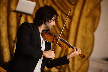 Musician violinist with a violin in his hands standing on stage during the concert. Around the...