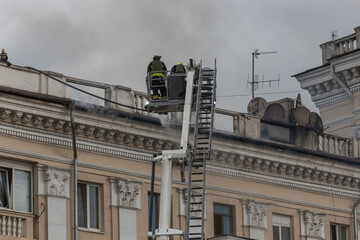 Rescuers are putting out the fire. A damaged residential building after a massive rocket attack. Heavy smoke. The house is on fire.
