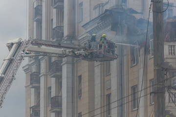 Naklejka premium Rescuers are putting out the fire. A damaged residential building after a massive rocket attack. Heavy smoke. The house is on fire.