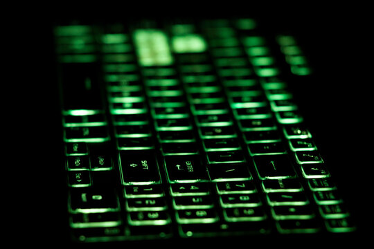 A laptop keyboard with green keys is lit up