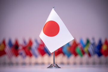 a small flag of japan is sitting in front of a row of other flags
