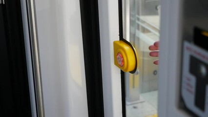 finger presses button to open doors in subway car.