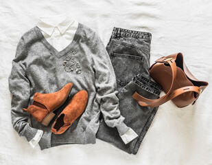 Urban style women's clothing - grey mom jeans, white shirt, grey pullover, brown suede chelsea and leather brown bag on a light background, top view - 789887809