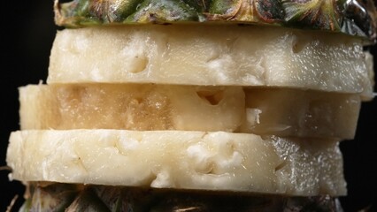Close up video of fresh pineapple with slice of peel pineapple insert with separated black background. The rough and waxy rind, boasting a crown of spiky green leaves, Food photography. Comestible.