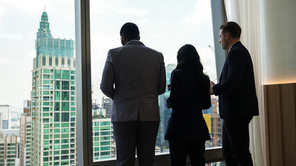 Back view diverse team of ambitious business people standing in ornamented office gazing out window...