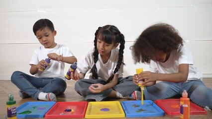 Group of diverse young student mixing color while sitting together. Happy multicultural children...