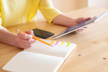 Unrecognizable Woman Organizing Household Tasks Using A Digital Tablet And Notepad. Homework Planning Concept.