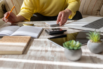 Woman Inside The Home Using A Calculator To Calculate Household Expenses And Accounting.