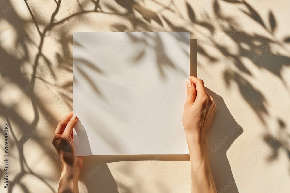 Poster hands holding a blank white paper with shadow patterns.