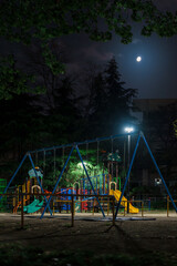 深夜の公園の遊具と月の見える風景