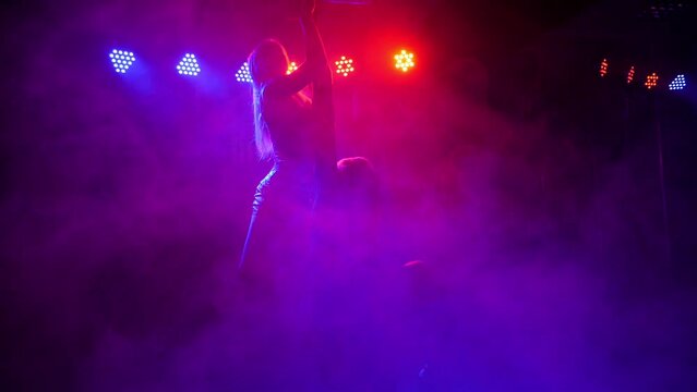 Two luxury girls dancing sensual erotic dance around the pole with the light on red lights. Slow motion. Pole dance.