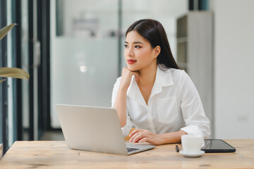 Beautiful young asian business woman using laptop at modern office