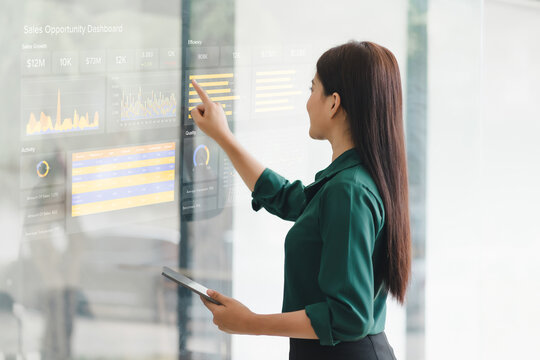 Businesswoman interacts with a digital sales dashboard displaying various performance metrics and analytics.
