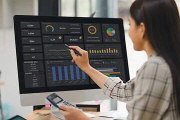 Businesswoman interacts with a digital sales dashboard displaying various performance metrics and analytics.