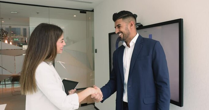 Latin and Indian businesspeople finish negotiations or formal meeting in office, shaking hands, gesture of agreement, partnership, express mutual respect. Make profitable commercial deal, reach goal