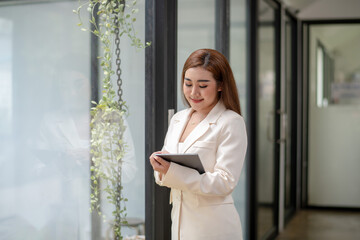 Portrait of a poised Asian businesswoman in a white suit standing confidently in a contemporary...