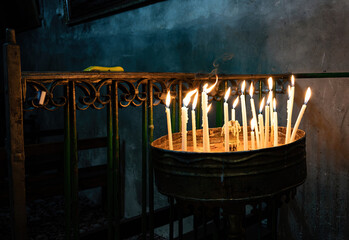 Burning church candles in an ancient temple in the darkness