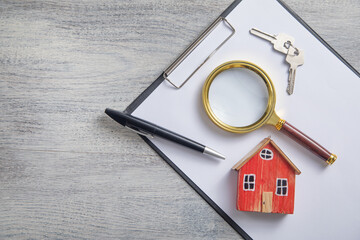 Magnifying glass, house model, pen, keys on the clipboard. - 789912657