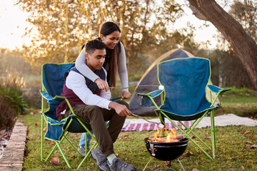 Fire, camping and couple with marshmallows in nature for romantic vacation, adventure or holiday....