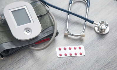 Digital blood pressure machine with a pills on the table.