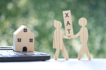 Love couple holding tax wooden text and model house on calculator on natural green...