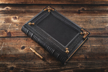 Aged black leather journal lay down to wooden table