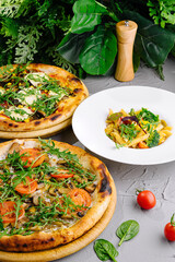 Gourmet vegetable pizzas and pasta on table