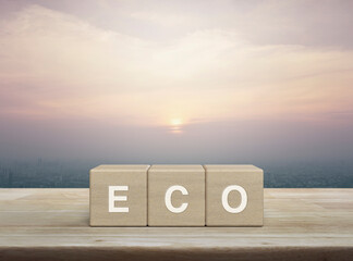 Eco letter on wood block cubes on wooden table over city tower and skyscraper at sunset, vintage...
