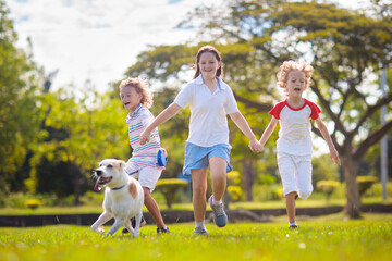 Kids play with dog. Children and puppy run in park - 789942052