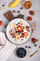 Fototapeta na wymiar Healthy Banana Split Breakfast with Yogurt, Granola and Fresh Berries