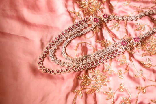diamond studded 3  tier gold chain placed on a silky satin cloth