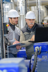 two technicians with laptop and clipboard checking pump