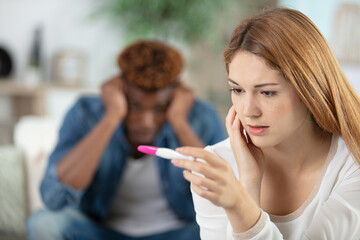 portrait of worried young couple holding pregnancy tester