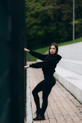 Young female workout before fitness training session at the park. Healthy young woman warming up outdoors. She is stretching her arms and looking away,hi key.