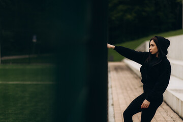 a woman in dark sportswear near a soccer field