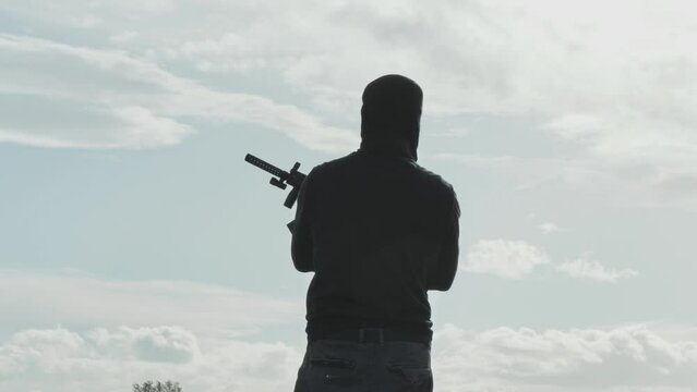 War,watchman stands guard holding rifle,back view of soldier sentinel with gun standing outdoor at the vantage point keeping eye on enemy