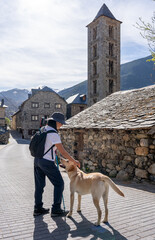 Woman hiker petting a dog just upon arrival at a new mountain town to visit on her trekking day - obrazy, fototapety, plakaty