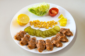 Cig kofte (raw meatball) with lettuce, tomato, pickle and lemon, hot Chee kofta. Turkish local raw food concept.Table scene of assorted take out or delivery foods. Top view of assorted Turkish food.