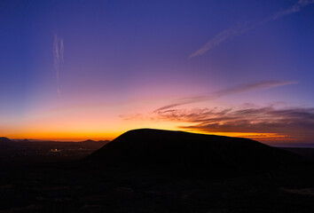 Beautiful aerial sunset image over Volcan Calderon Hondo volcanic crater silhouetted against the setting sun and skyscape near Corralejo, Fuerteventura, Canary Islands, Spain