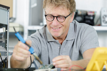 man testing circuit board in his office