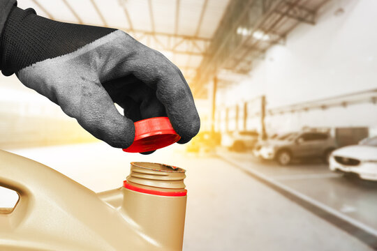 Auto mechanic hand is opening the cap of a gallon of motor oil in the auto repair shop , Car maintenance service concept