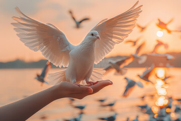 Open hands release doves into the sky at sunset, symbolizing freedom and hope, against the backdrop of a serene lake with birds flying in the distance. - obrazy, fototapety, plakaty