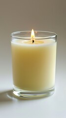 A single lit candle in a glass jar against a pale grey background.