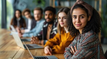 A diverse group of individuals sitting at a table, each engaged with a laptop computer, working or collaborating on a project together