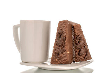 Two pieces of chocolate waffle cake with cup on white ceramic saucer, macro, isolated on white background.