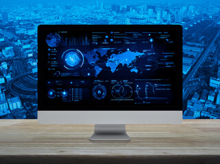 Computer with digital world map with data charts and stats screen on wooden table over city tower, street, expressway and skyscraper, Futuristic user interface technology online concept