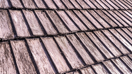 Close up of wood texture and background. Natural cedar shingle siding. Rough bumpy wood shingle cladding, row of wooden material of small shingle wall facade